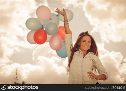 holidays, celebration and lifestyle concept - attractive woman female model holding bunch of colorful balloons outside cloudy sky background. Aged tone