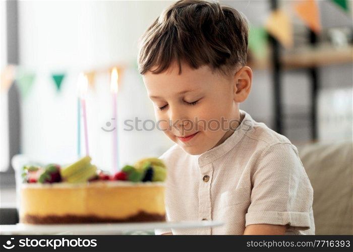 holidays, celebration and people concept - close up of happy little boy with birthday cake at home party making wish. happy little boy blowing candles on birthday cake