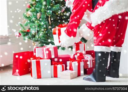 holidays, celebration and people concept - close up of santa claus putting present under christmas tree at home