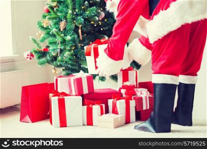 holidays, celebration and people concept - close up of santa claus putting present under christmas tree