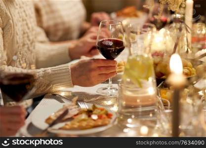 holidays, celebration and people concept - friends having christmas dinner party and drinking non-alcoholic red wine at home. friends drinking red wine at christmas party
