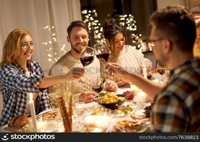 holidays, celebration and people concept - happy friends having christmas dinner party and drinking non-alcoholic red wine at home. happy friends drinking red wine at christmas party