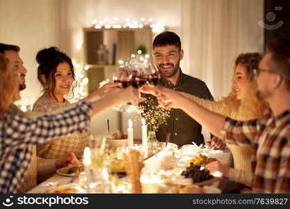 holidays, celebration and people concept - happy friends having christmas dinner party drinking non-alcoholic red wine at home. happy friends drinking red wine at christmas party