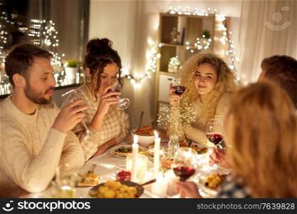 holidays, celebration and people concept - happy friends having christmas dinner party and drinking non-alcoholic red wine at home. happy friends drinking red wine at christmas party