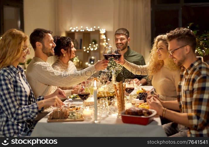 holidays, celebration and people concept - happy friends having christmas dinner party and drinking non-alcoholic red wine at home. happy friends drinking red wine at christmas party