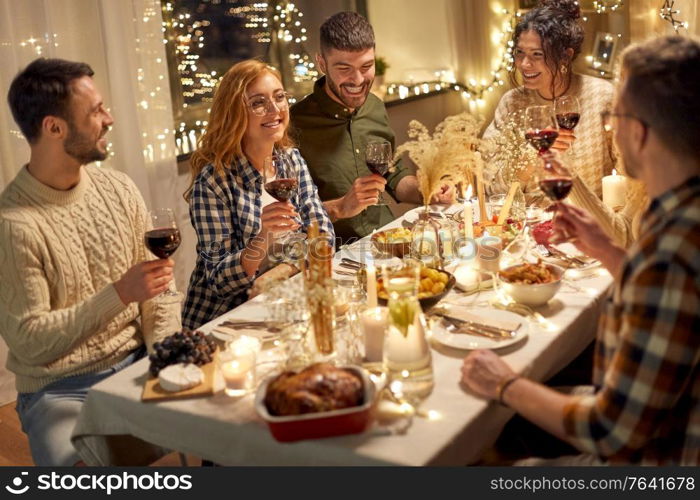 holidays, celebration and people concept - happy friends having christmas dinner party and drinking non-alcoholic red wine at home. happy friends drinking red wine at christmas party