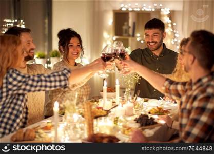 holidays, celebration and people concept - happy friends having christmas dinner party drinking non-alcoholic red wine at home. happy friends drinking red wine at christmas party