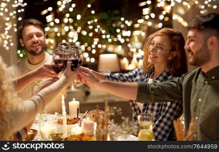holidays, celebration and people concept - happy friends having christmas dinner party drinking non-alcoholic red wine at home. happy friends drinking red wine at christmas party