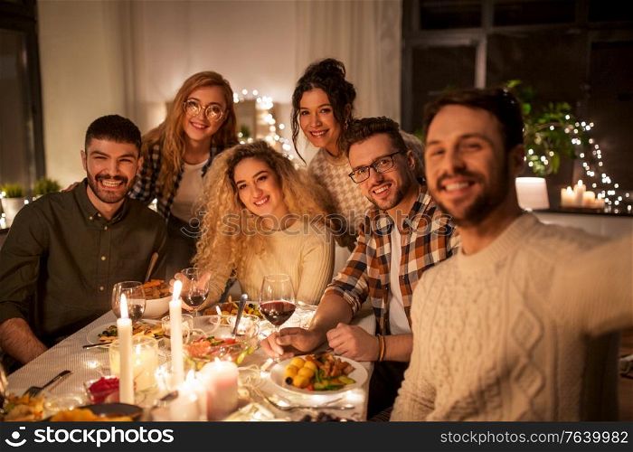 holidays, celebration and people concept - happy friends taking selfie at home christmas dinner party. friends taking selfie at christmas dinner party