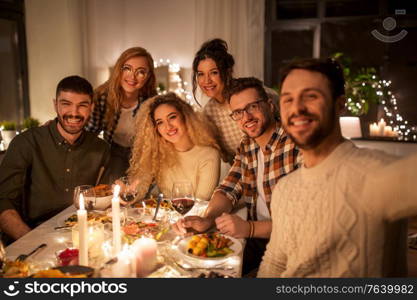 holidays, celebration and people concept - happy friends taking selfie at home christmas dinner party. friends taking selfie at christmas dinner party