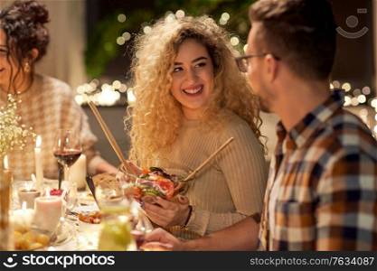 holidays, celebration and people concept - happy smiling friends having christmas dinner at home in evening. happy friends having christmas dinner at home