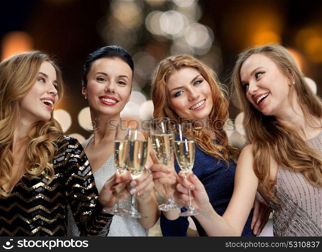 holidays, celebration and people concept - happy women clinking non alcoholic champagne glasses at new year party over christmas tree lights background. happy women drinking champagne at christmas