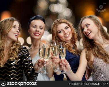 holidays, celebration and people concept - happy women clinking non alcoholic champagne glasses at new year party over christmas tree lights background. happy women drinking champagne at christmas