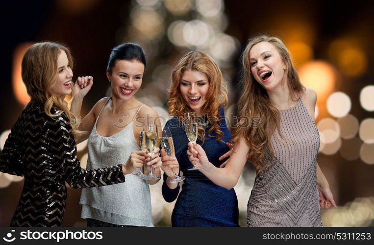 holidays, celebration and people concept - happy women clinking non alcoholic champagne glasses at new year party over christmas tree lights background. happy women drinking champagne at christmas