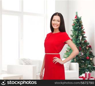 holidays, celebration and people concept - smiling woman in red dress over living room and christmas tree background
