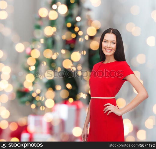 holidays, celebration and people concept - smiling woman in red dress over christmas tree background