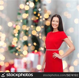 holidays, celebration and people concept - smiling woman in red dress over christmas tree background