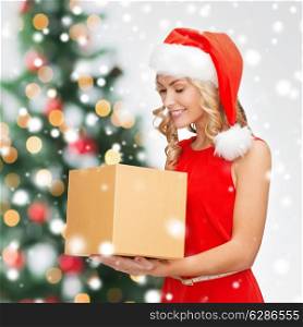 holidays, celebration and people concept - smiling woman in santa helper hat and red dress with gift box over christmas tree lights background