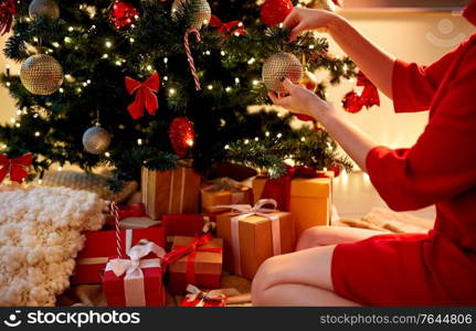 holidays, celebration and people concept - woman hands decorating christmas tree with ball. hands decorating christmas tree with ball