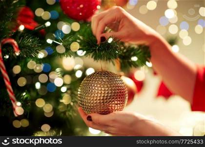 holidays, celebration and people concept - woman hands decorating christmas tree with ball. hands decorating christmas tree with ball