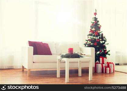 holidays, celebration, decoration and interior concept - sofa, table and christmas tree with gifts at home. sofa, table and christmas tree with gifts at home