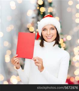 holidays, celebration, greeting and people concept - smiling woman in santa helper hat with greeting card over living room and christmas tree background