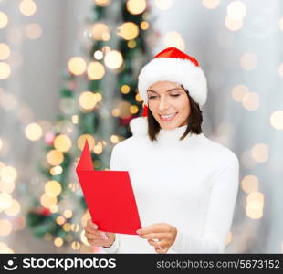 holidays, celebration, greeting and people concept - smiling woman in santa helper hat with greeting card over living room and christmas tree background