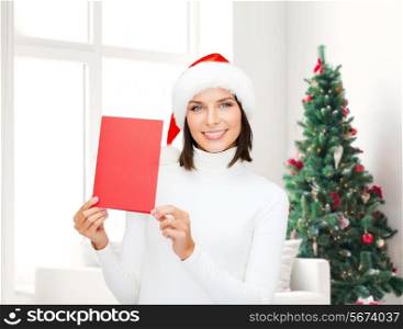 holidays, celebration, greeting and people concept - smiling woman in santa helper hat with greeting card over living room and christmas tree background