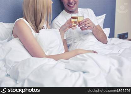 holidays, celebration, romance and people concept concept - close up of smiling couple with champagne glasses in bed