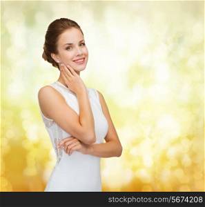 holidays, celebration, wedding and people concept - smiling woman in white dress wearing diamond ring over golden lights background