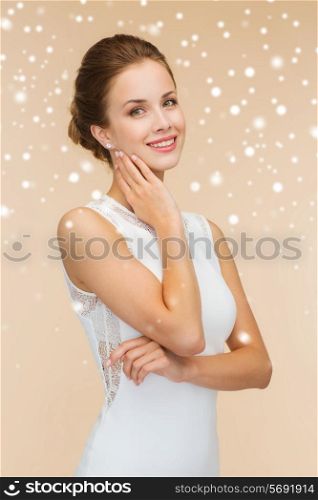holidays, celebration, wedding and people concept - smiling woman in white dress wearing diamond ring over beige background and snow