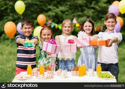 holidays, childhood and celebration concept - happy kids with gifts on birthday party at summer garden. happy kids with gifts on birthday party at summer. happy kids with gifts on birthday party at summer