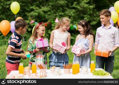 holidays, childhood and celebration concept - happy kids with gifts on birthday party at summer garden. happy kids with gifts on birthday party at summer. happy kids with gifts on birthday party at summer