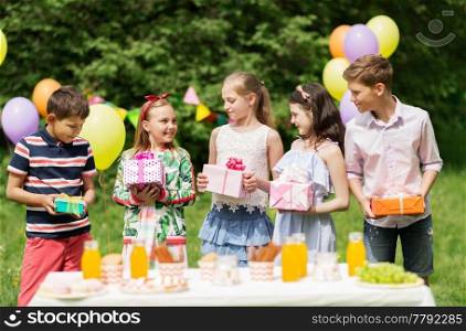 holidays, childhood and celebration concept - happy kids with gifts on birthday party at summer garden. happy kids with gifts on birthday party at summer