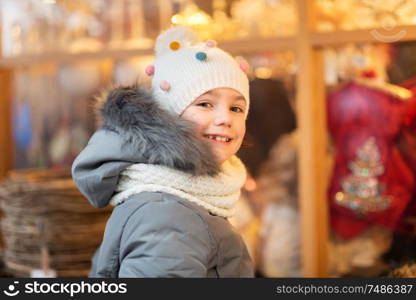 holidays, childhood and people concept - happy little girl at christmas market in winter. happy little girl at christmas market in winter