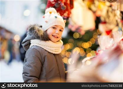 holidays, childhood and people concept - happy little girl at christmas market in winter. happy little girl at christmas market in winter