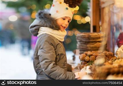 holidays, childhood and people concept - happy little girl at christmas market in winter. happy little girl at christmas market in winter