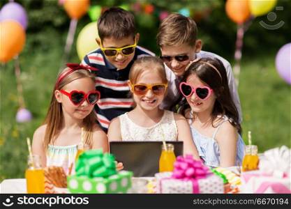 holidays, childhood and technology concept - happy kids in sunglasses with tablet pc on birthday party at summer garden. happy kids with tablet pc on birthday party. happy kids with tablet pc on birthday party