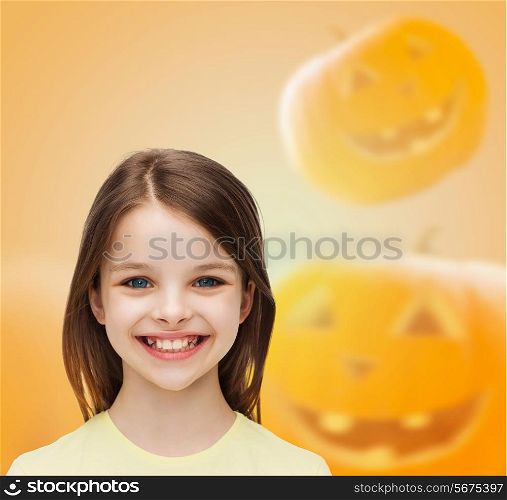 holidays, childhood, happiness and people concept - smiling little girl over halloween pumpkins background