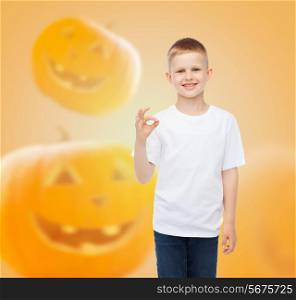 holidays, childhood, happiness, gesture and people concept - smiling little boy in white blank shirt showing ok sign over halloween pumpkins background