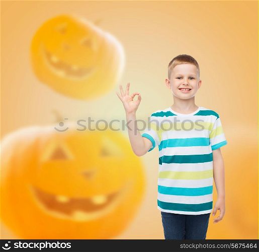 holidays, childhood, happiness, gesture and people concept - smiling little boy showing ok sign over halloween pumpkins background
