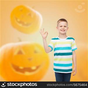 holidays, childhood, happiness, gesture and people concept - smiling little boy showing ok sign over halloween pumpkins background
