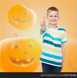 holidays, childhood, happiness, gesture and people concept - smiling little boy showing thumbs up over halloween pumpkins background