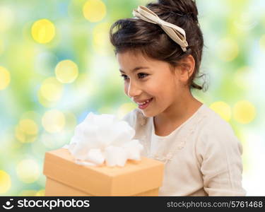 holidays, children, christmas, people and birthday concept - happy little girl with gift box over green lights background