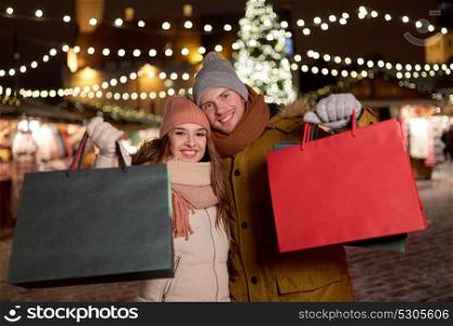 holidays, christmas and people concept - happy couple at with shopping bags in winter. happy couple at with shopping bags in winter