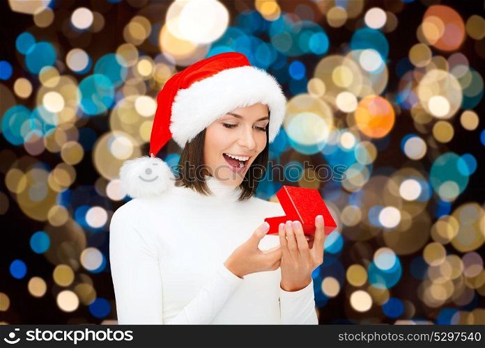 holidays, christmas and people concept - happy woman in santa hat opening gift box over lights background. happy woman in santa hat opening christmas gift