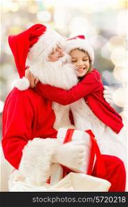 holidays, christmas, childhood and people concept - smiling little girl hugging with santa claus over lights background