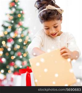 holidays, christmas, childhood and people concept - smiling little girl with gift box at home