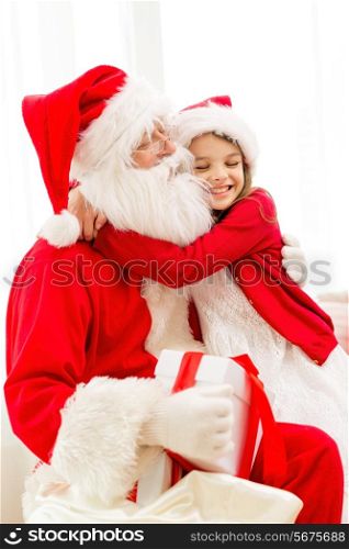 holidays, christmas, happiness and people concept - smiling girl with gift box embracing santa claus at home