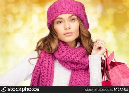 holidays, christmas, sale and people concept - young woman in winter clothes with shopping bags over lights background